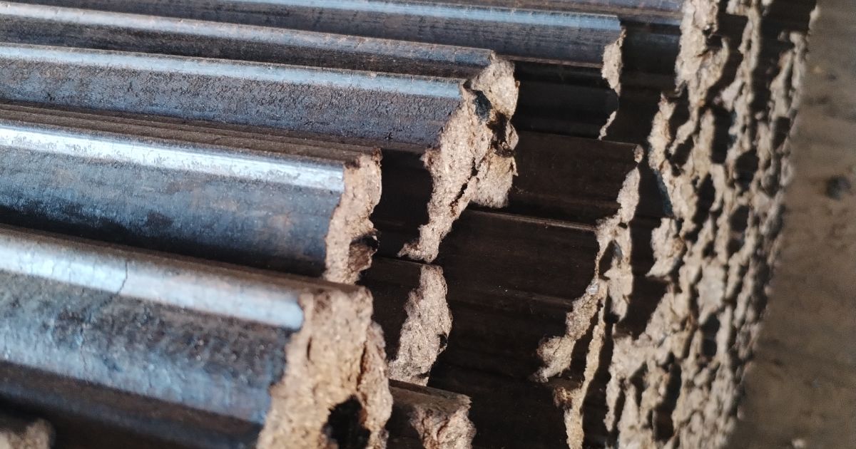 Close-up of a stack of compressed wood briquettes for fuel, showing their textured surface and fibrous ends.