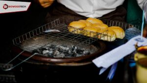 A professional charcoal grill with glowing embers and a wire rack holding buns, showcasing Biowoodtech’s premium restaurant-grade charcoal in a commercial food setting.